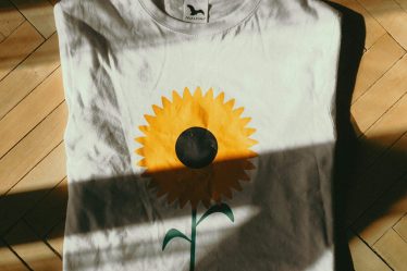 https://unsplash.com/photos/a-white-t-shirt-with-a-yellow-flower-painted-on-it-TWbEzeuIFzI?utm_content=creditShareLink&utm_medium=referral&utm_source=unsplash