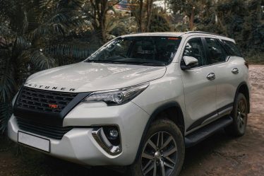 https://unsplash.com/photos/a-white-car-parked-on-a-dirt-road-with-trees-and-a-building-in-the-background-9Px9UR-wZkQ?utm_content=creditShareLink&utm_medium=referral&utm_source=unsplash